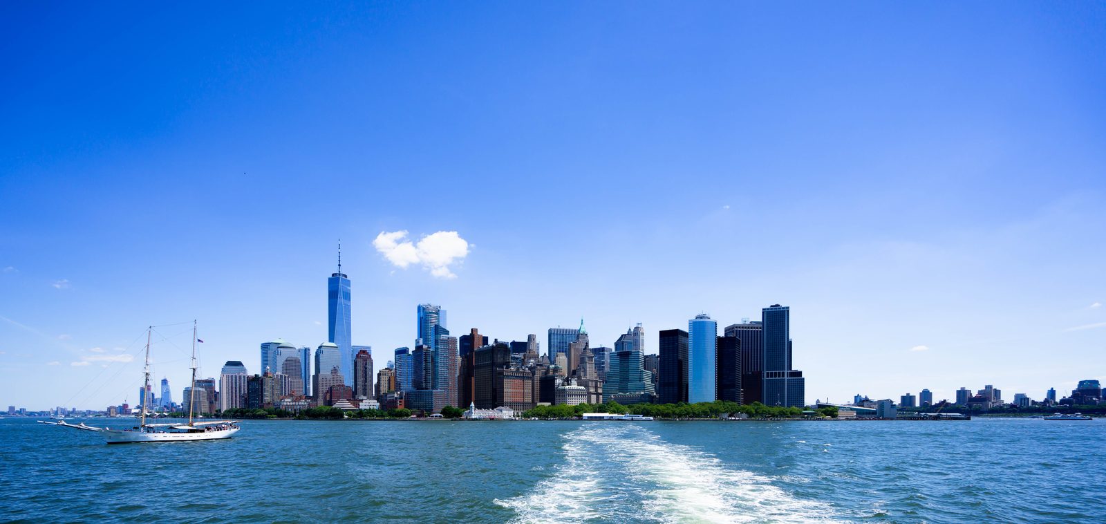 Lower Manhattan skyline from the harbor with a sailboat passing